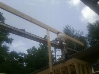 Carpenter setting a ridge beam over a new addition frame — Ice Dam Removal by Roofing Brothers in Cerro Gordo