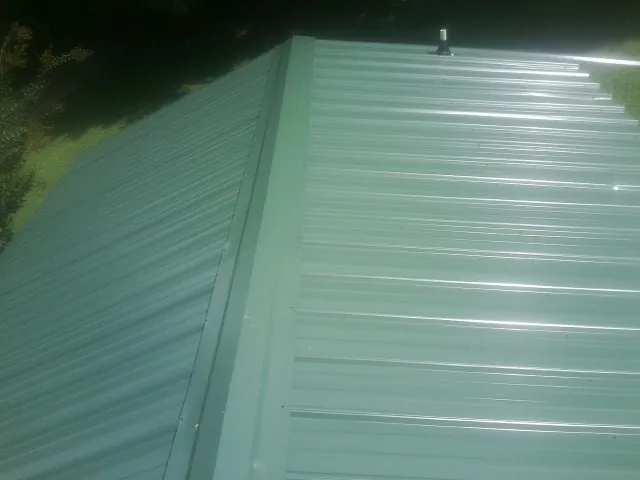 New green metal panels meeting at the ridge of a roof — Flat Roof Repair work by our crew in Cerro Gordo